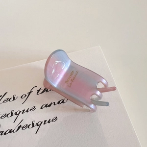 Close-up of a gradient acetate hair claw clip with pearlescent finish and gold lettering