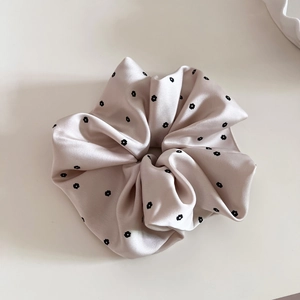 Detail of light pink satin scrunchie with delicate black floral print and pleated texture