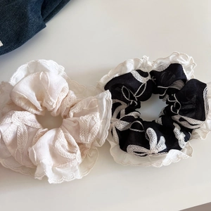 Détails de chouchous brodés beiges et noirs avec motifs floraux et bordures en dentelle