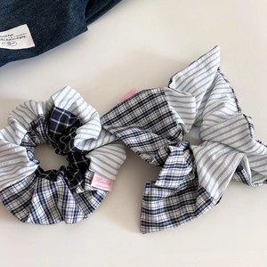 Detailed view of handmade striped and plaid scrunchies with elegant pink woven label
