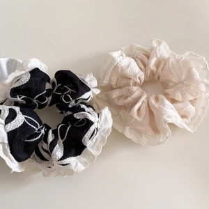 Gros plan de chouchous en dentelle brodée beige et noir avec motif floral à volants