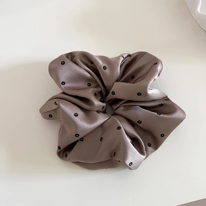 Detailed view of the brown satin scrunchie with a black floral pattern and silky texture