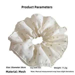 Detailed view of oversized white tulle scrunchie with gold sequins, 20cm diameter