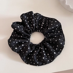 Détail du grand chouchou à pois noirs avec une texture douce en satin de soie plissé
