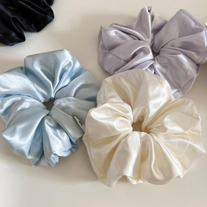 Detail showing various colors of glossy satin scrunchies with elegant silk texture