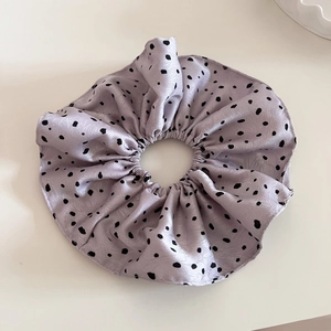 Détail d'un chouchou géant en satin lavande à pois noirs avec une texture douce et soyeuse