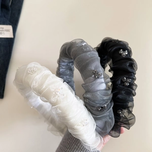 Détail de trois serre-têtes en organza plissé avec fleurs perlées en noir, gris et blanc