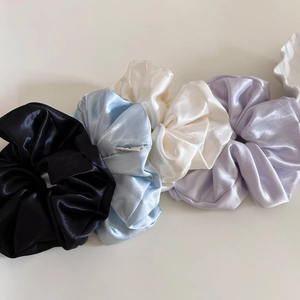 Detail of four glossy satin silk scrunchies in black blue white and purple colors