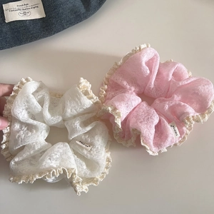 Pink and white lace scrunchies with crochet edges and stylish woven brand labels