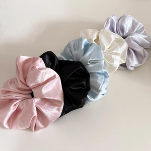 Selection of glossy satin scrunchies in pastel pink, blue, black, cream, and violet colors
