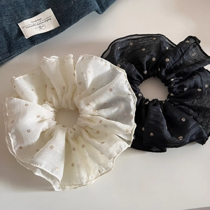 Detail view of large mesh hair scrunchies in cream and black with gold polka dots