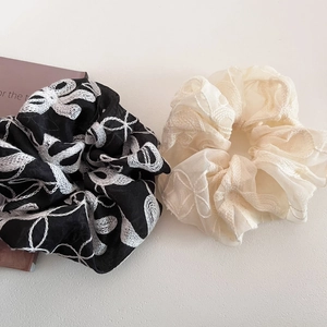 Détails de la broderie de fleurs en dentelle sur les chouchous beige et noir élégants