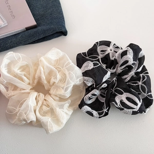 Vue détaillée de chouchous en organza beige et noir avec broderie florale et nœuds