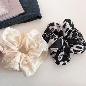 Détail de chouchous crème et noirs avec de broderies florales blanches délicates