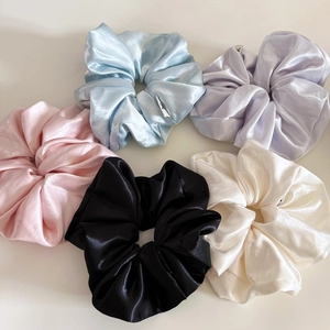 Detailed view of five multi-colored glossy satin scrunchies in elegant pastel shades