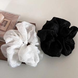 Close-up of black and white polka dot mesh hair scrunchies on a rustic wooden tray