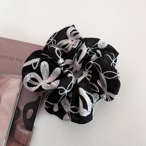 Gros plan d'un chouchou élégant en dentelle noire avec broderie florale blanche