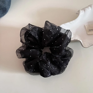 Détail d'un chouchou en résille noire avec pois argentés et paillettes scintillantes