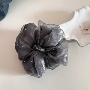 Détail d'un chouchou en organza gris foncé avec des paillettes argentées scintillantes