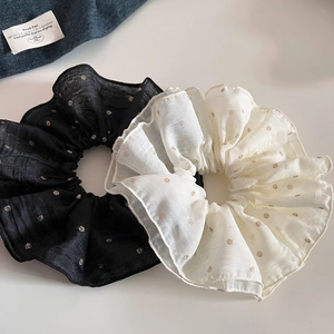 Detailed view of large mesh scrunchies with gold polka dots in black and beige colors