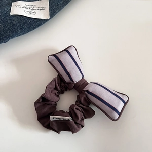 Détail d'un chouchou vintage avec nœud en coton rayé et étiquette de marque tissée