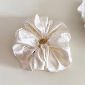 Detail of elegant pearl white satin scrunchie showing glossy fabric texture and soft folds