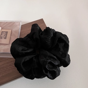 Detail of elegant black mesh scrunchie with 3D polka dots on a vintage background