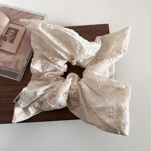 Close-up of cream beige floral embroidery lace scrunchie with delicate fabric texture