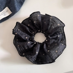 Detail shot of a black organza scrunchie with metallic dots and pleated layers