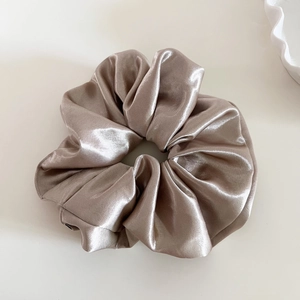 Detailed view of champagne gold satin scrunchie with soft pleats and elegant silk texture