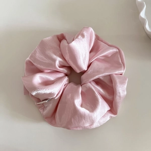 Macro detail of glossy pink satin scrunchie showing fabric texture and pleated folds