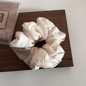 Elegant off-white lace floral embroidered scrunchie on a dark walnut wooden tray