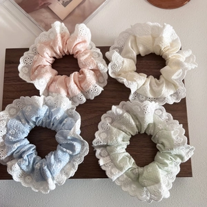 Dettaglio di quattro elastici in pizzo floreale in colori pastello su legno