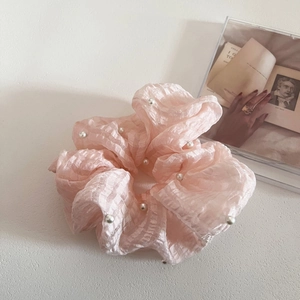 Détail du chouchou en seersucker rose avec perles blanches sur un fond de décor épuré