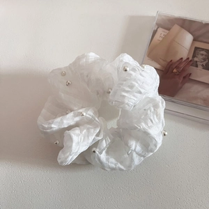 Gros plan d'un chouchou en seersucker blanc cassé avec perles élégantes sur magazine