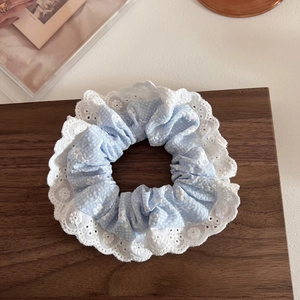 Dettaglio del tessuto floreale blu con pizzo ricamato bianco sull'elastico per capelli