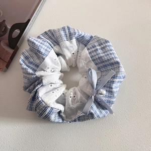 Detail of blue plaid fabric scrunchie with lace edges and a faux pearl bow ornament