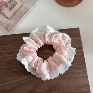 Dettaglio dell'elastico per capelli con tessuto a fiori rosa e pizzo ricamato bianco