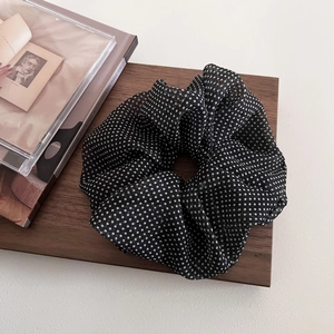 Macro shot of large black and white polka dot mesh scrunchie on a wooden display board
