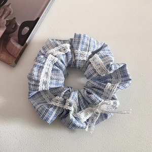 Detail of blue plaid cotton scrunchie with delicate white lace trim and pearl bow accent