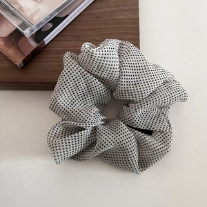 Close-up of French vintage mesh scrunchie with black polka dots on beige fabric
