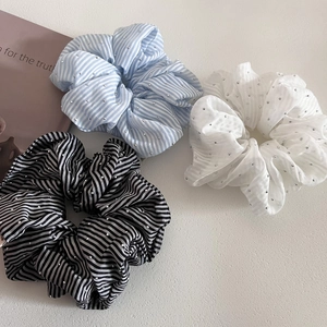 Close-up of striped and white scrunchies with sparkling rhinestone accents on white fabric