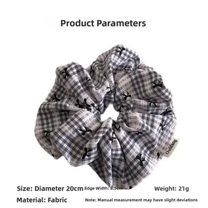 Detail view of large 20cm plaid hair scrunchie with black bow pattern and fabric texture