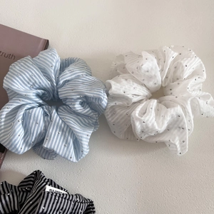 Close-up of striped scrunchies with silver studs on cream textured background