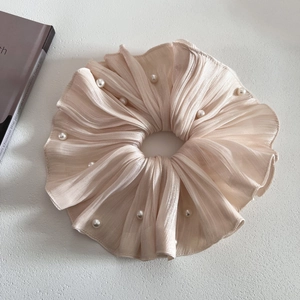 Détail d'un chouchou en soie rose champagne avec des perles blanches décoratives