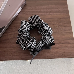 Détail d'un chouchou rayé avec des strass brillants et un accessoire de nœud noir