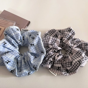 Close-up of plaid scrunchie set in light blue and black-white patterns with logo detail