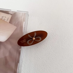 Brown acetate oval hair clip with sparkling bow design and champagne rhinestone embellishment