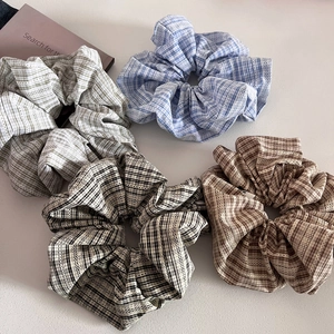 Detail of four plaid scrunchies with lace splicing on a clean aesthetic background