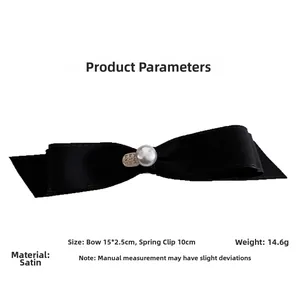 Detail of black satin bow hair clip with pearl and heart pendant and metal spring clip